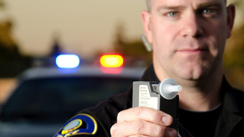 Officer Holding Up a PBT Device to an Individual Thinking "Will I Go to Jail for a DUI?"